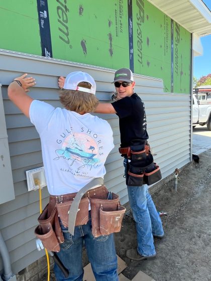 IKM Manning putting siding up on a house